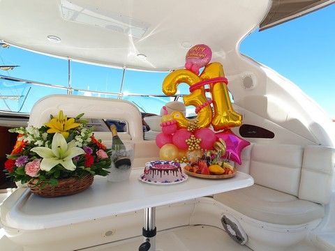 Number balloons, flowers and a cake set up in the cockpit of a motor yacht