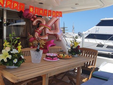 Birthday balloons, flowers and cake arranged on an aft-deck table aboard a yacht