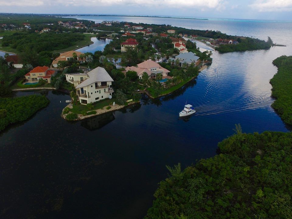 Aerial view of waterfront homes along a winding canal with a boat underway