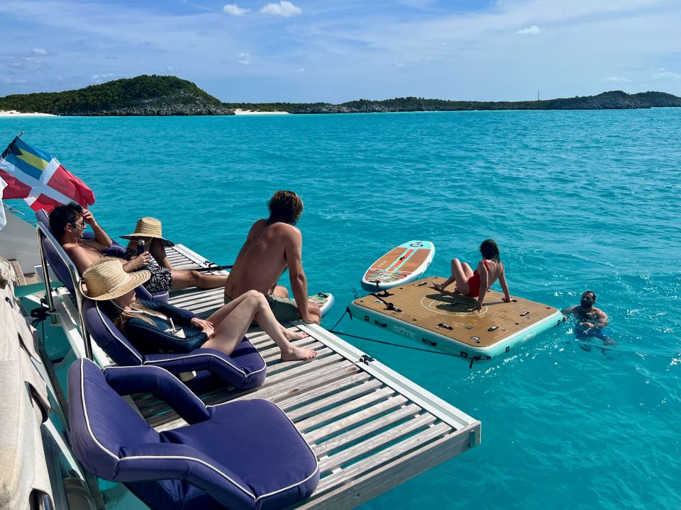 Guests relaxing on the stern of a catamaran beside a floating swim platform