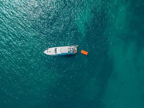 Bird's-eye view of a small yacht on open blue-green water