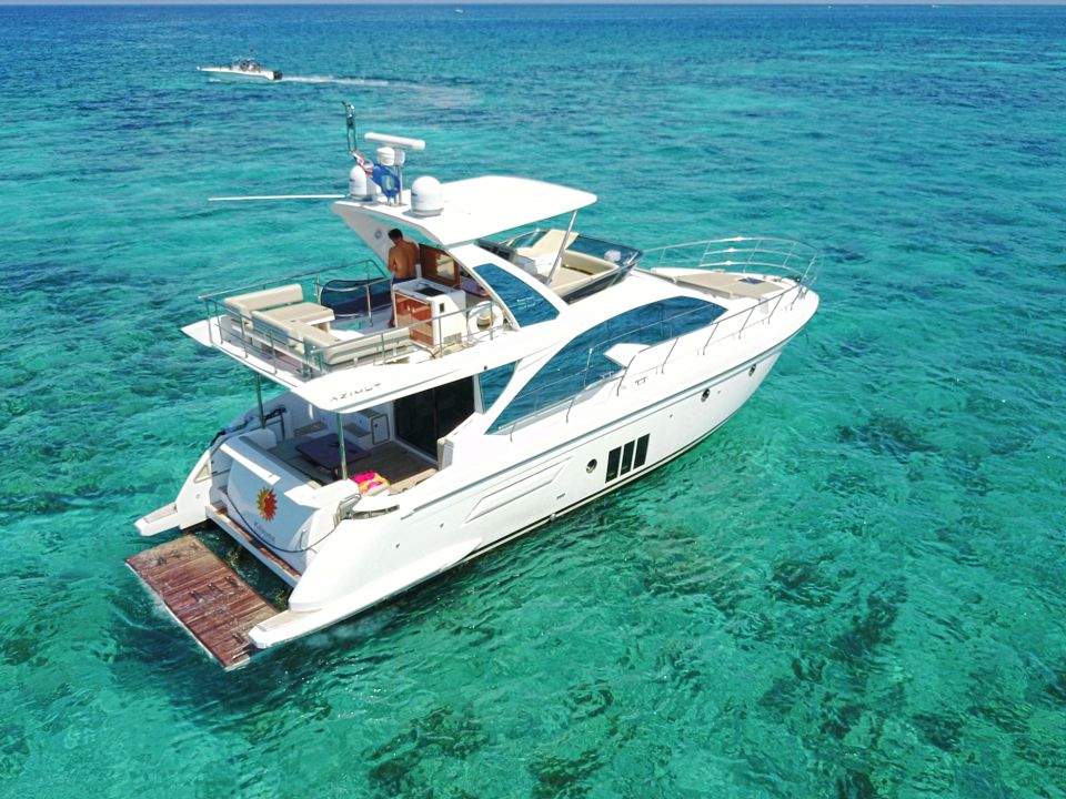 Aerial view of a flybridge yacht anchored in clear turquoise shallows