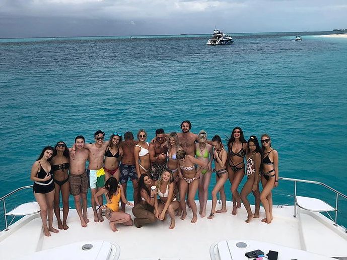 Large group of friends posing on the bow of a power catamaran