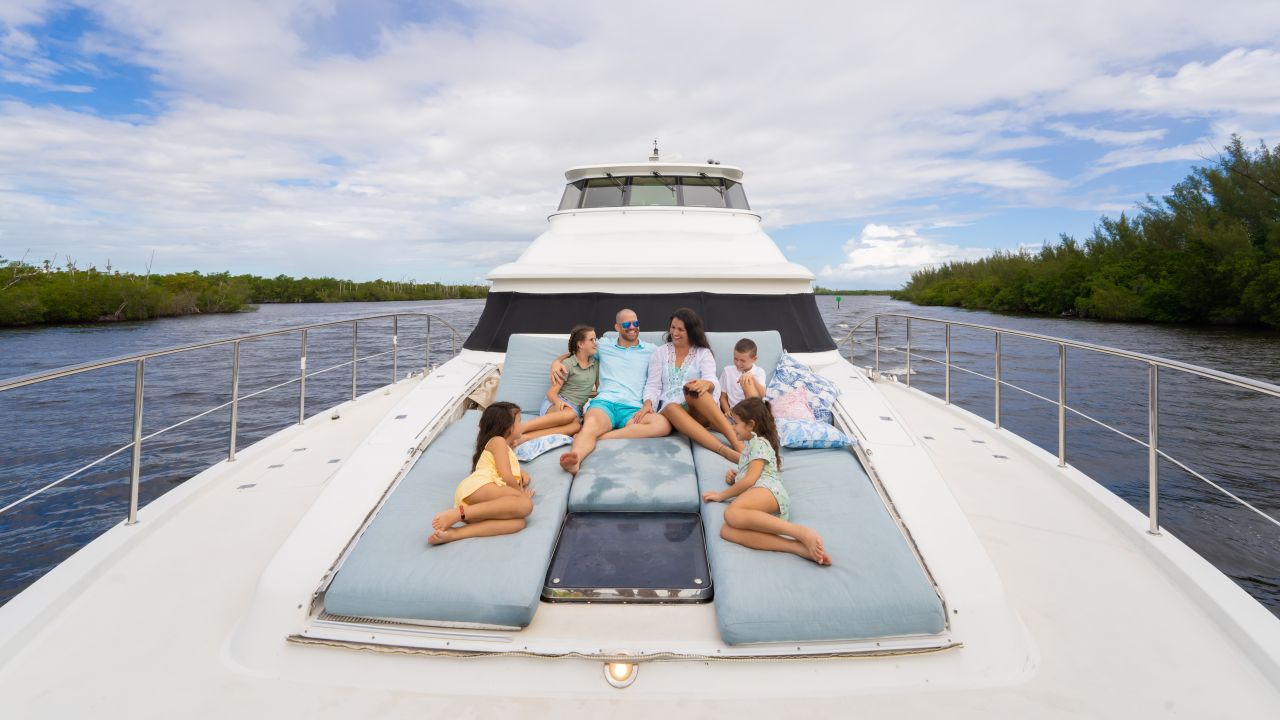 Family of five relaxing together on the bow sun pads of a motor yacht on a calm channel