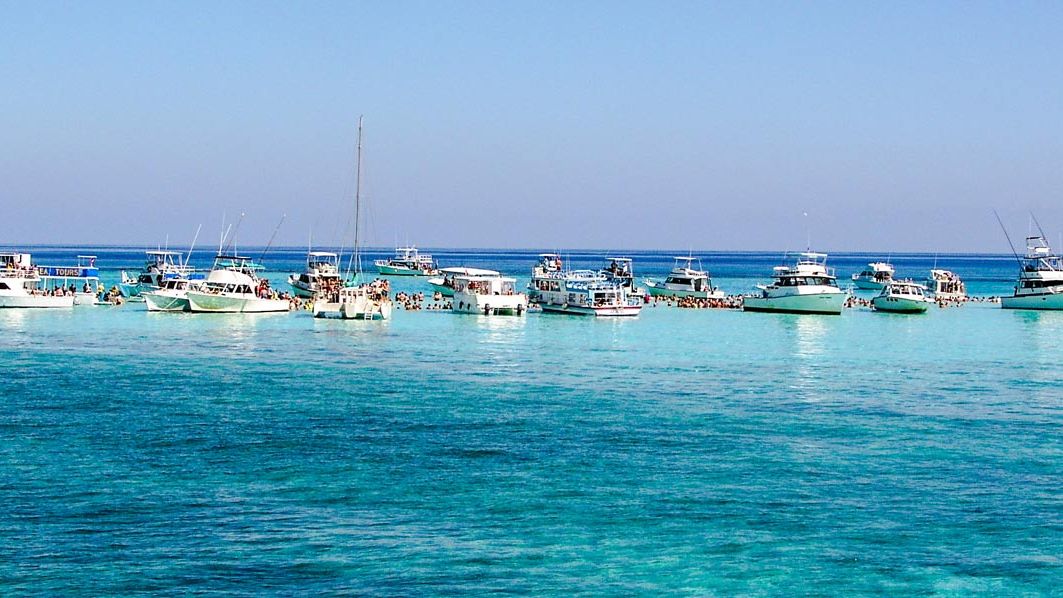A line of boats gathered on the shallow sandbar in Grand Cayman's North Sound under a clear sky