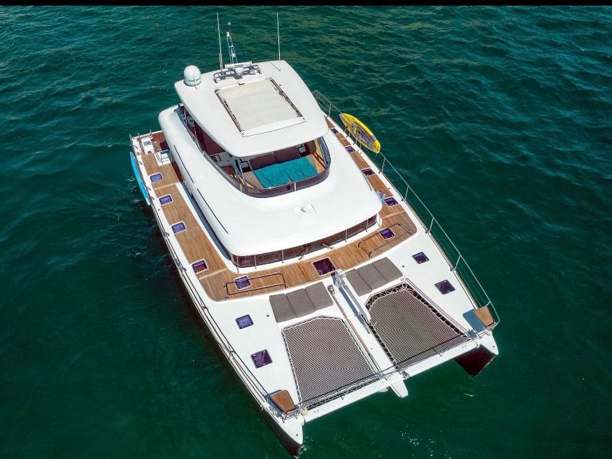 Aerial view of a large power catamaran with wide decks on dark green water