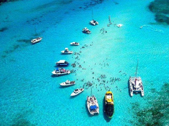 Aerial view of many boats anchored around the turquoise Stingray City Sandbar