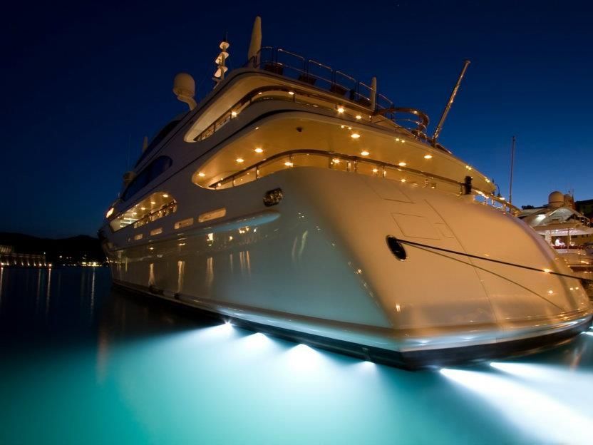 Superyacht illuminated in the evening with underwater lights glowing