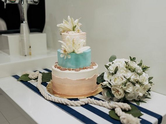 Tiered cake and white flowers on a table aboard a yacht