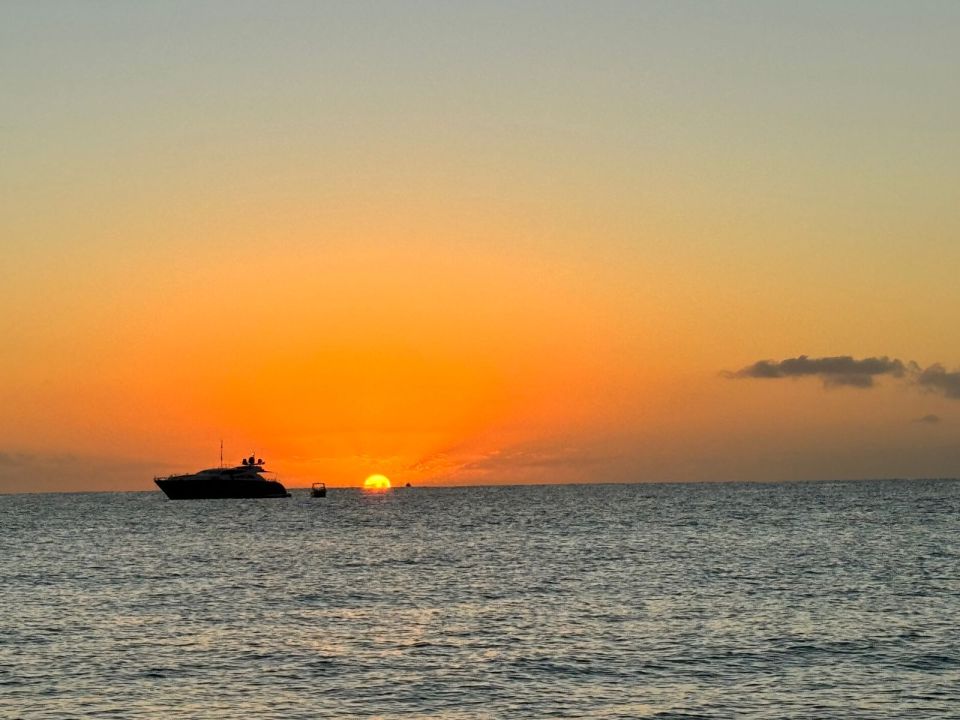 Yacht silhouetted on the horizon against an orange sunset